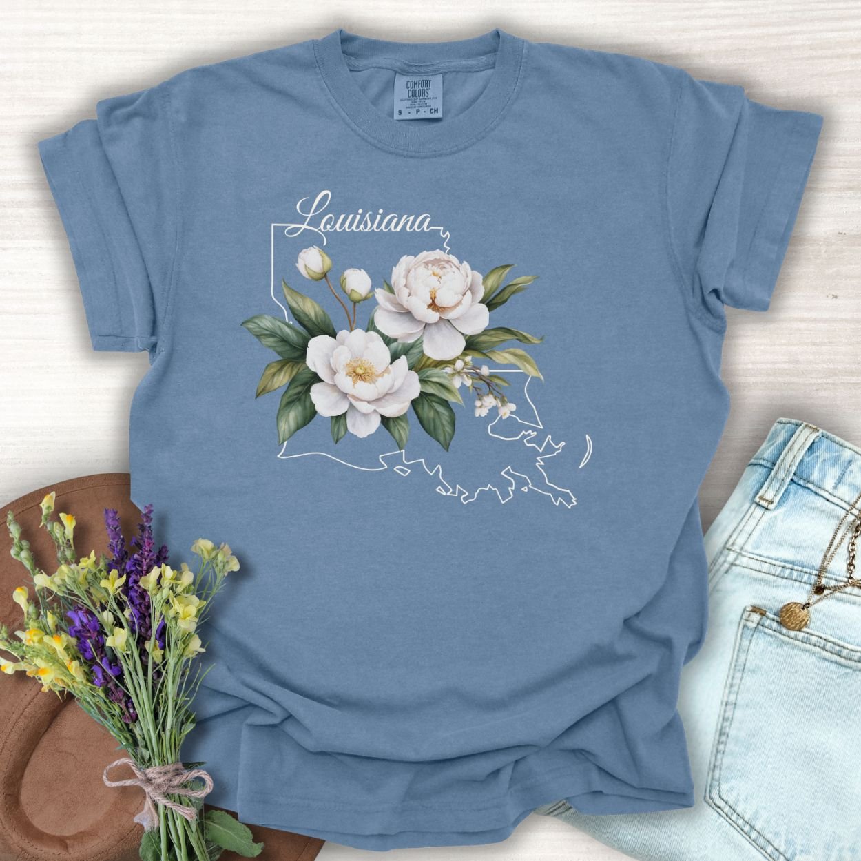 Blue Jean Louisiana State Flower T-Shirt with white magnolia illustration over a subtle Louisiana outline.