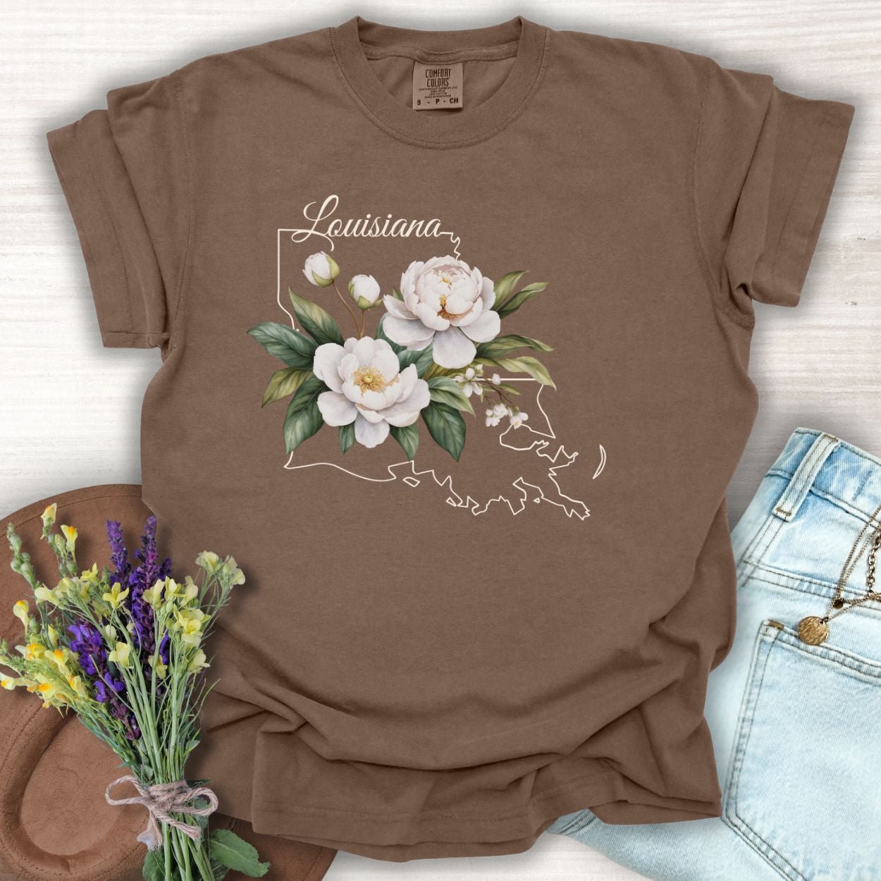 Espresso garment-dyed cotton t-shirt with a white magnolia illustration over a Louisiana outline.
