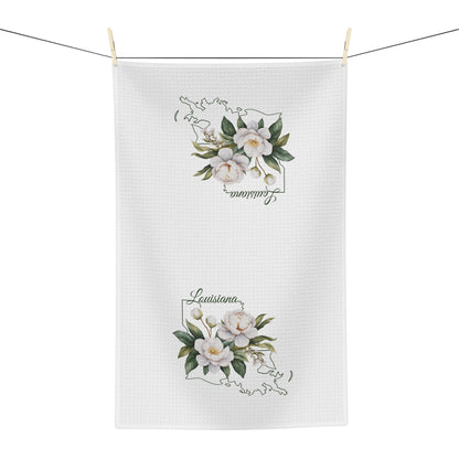 White microfiber tea towel with hand-drawn magnolias and "Louisiana" text over a state outline.