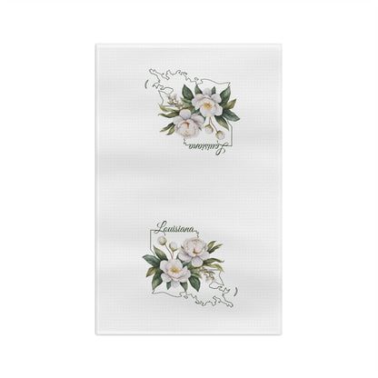 White microfiber tea towel with hand-drawn magnolias and "Louisiana" text over a state outline.
