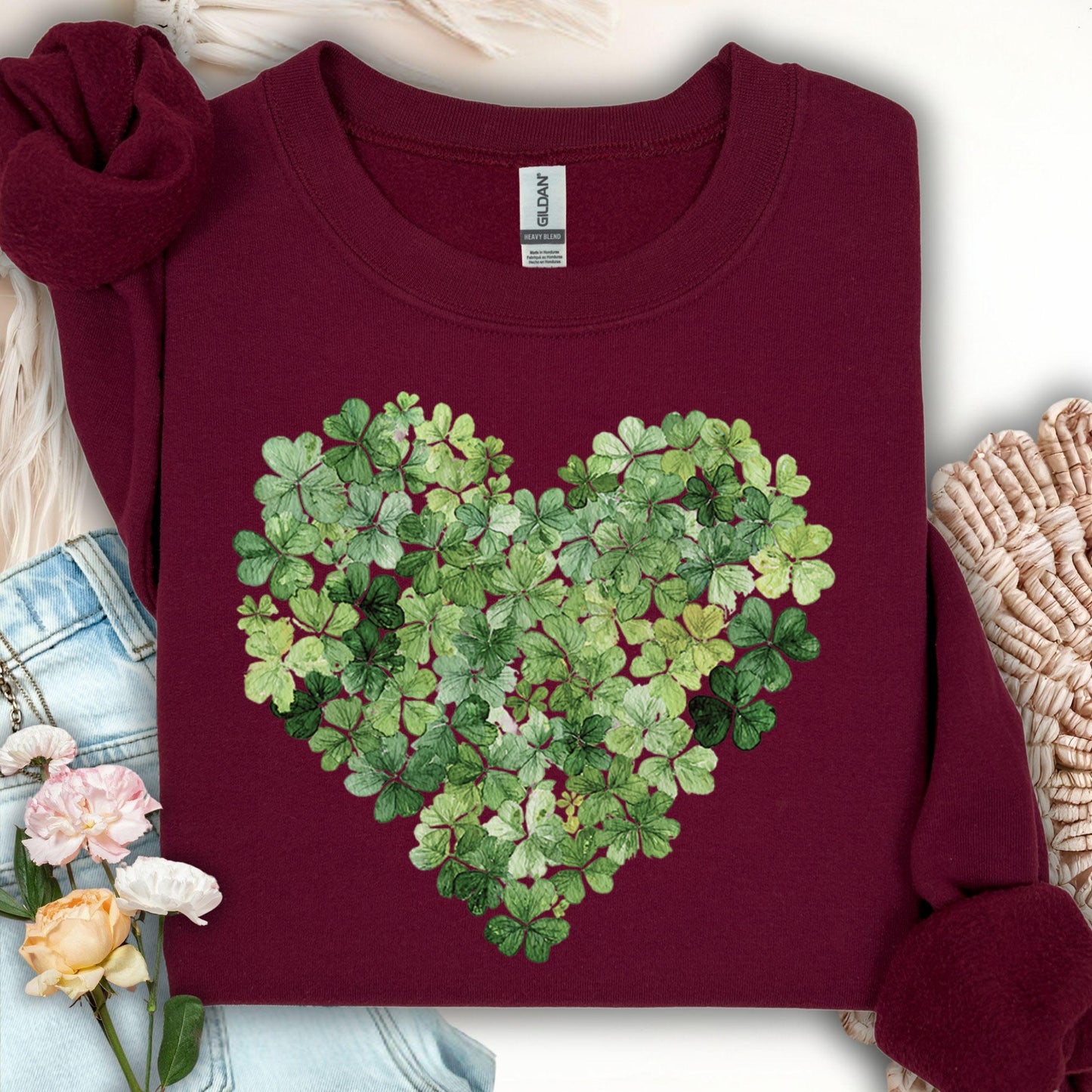 Maroon sweatshirt with a heart-shaped design made of green four-leaf clovers.