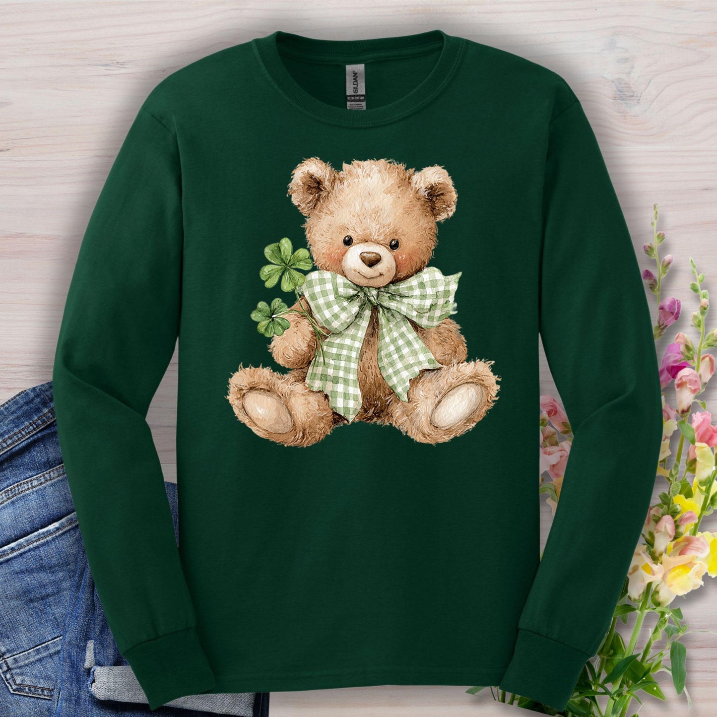 Forest Green long-sleeve tee with a watercolor teddy bear holding clovers and wearing a checkered bow.