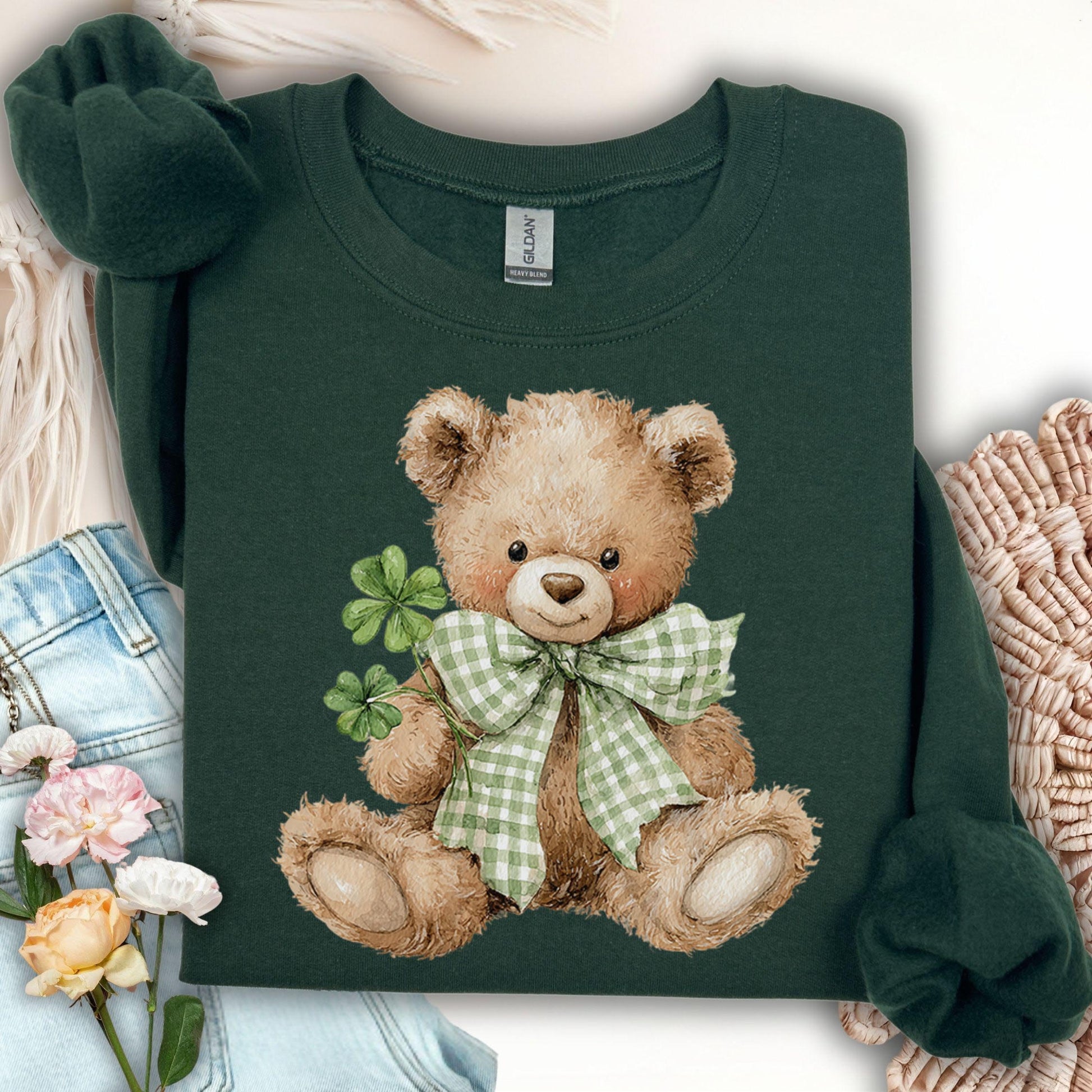 Dark green sweatshirt with a watercolor teddy bear wearing a shamrock bow and holding four-leaf clovers.