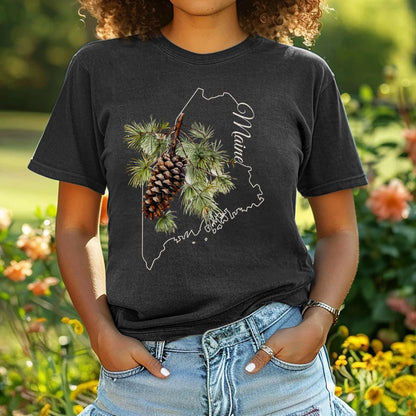 Garment-dyed black tee with a hand-painted pine cone and branch over a white outline of Maine.