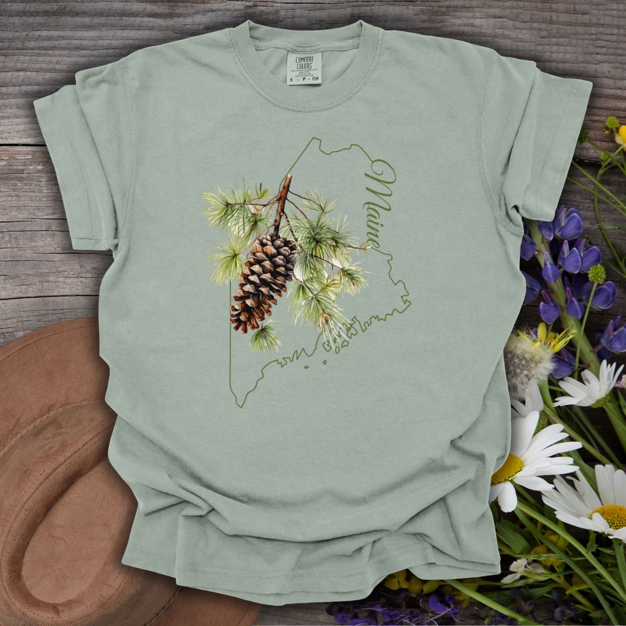 Bay S t-shirt with Maine outline and hand-painted pine cone and branch design.