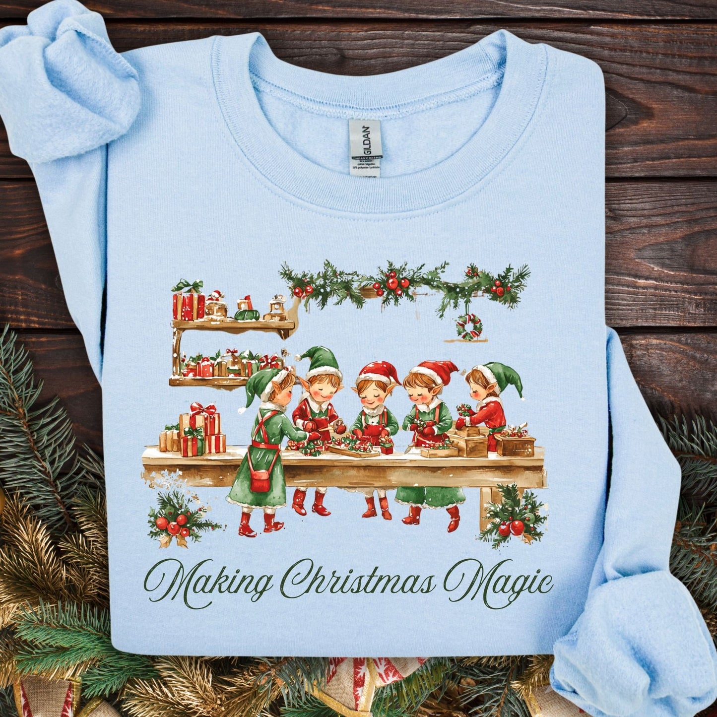 Light blue S sweatshirt with vintage Santa's workshop, elves, gifts, and "Making Christmas Magic" text.