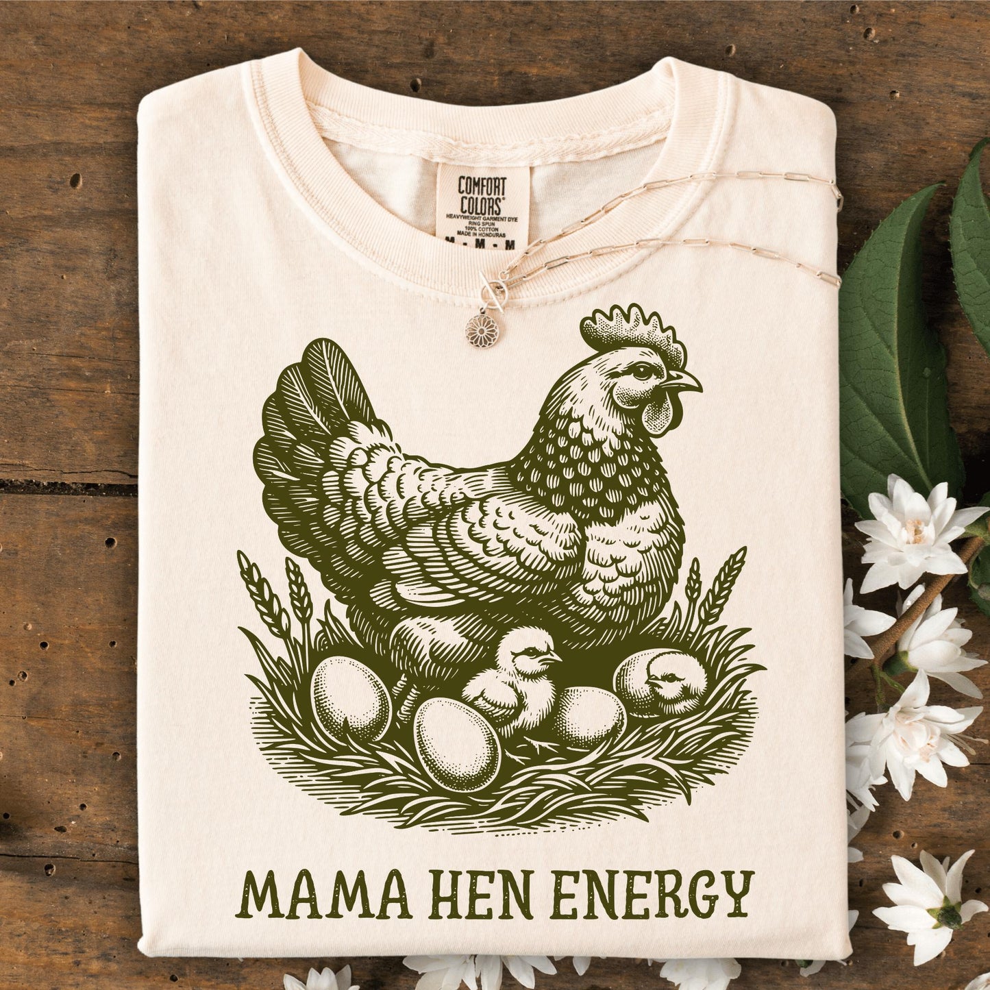 Ivory Comfort Colors t-shirt with a vintage green hen, chicks, eggs, and "Mama Hen Energy" text.