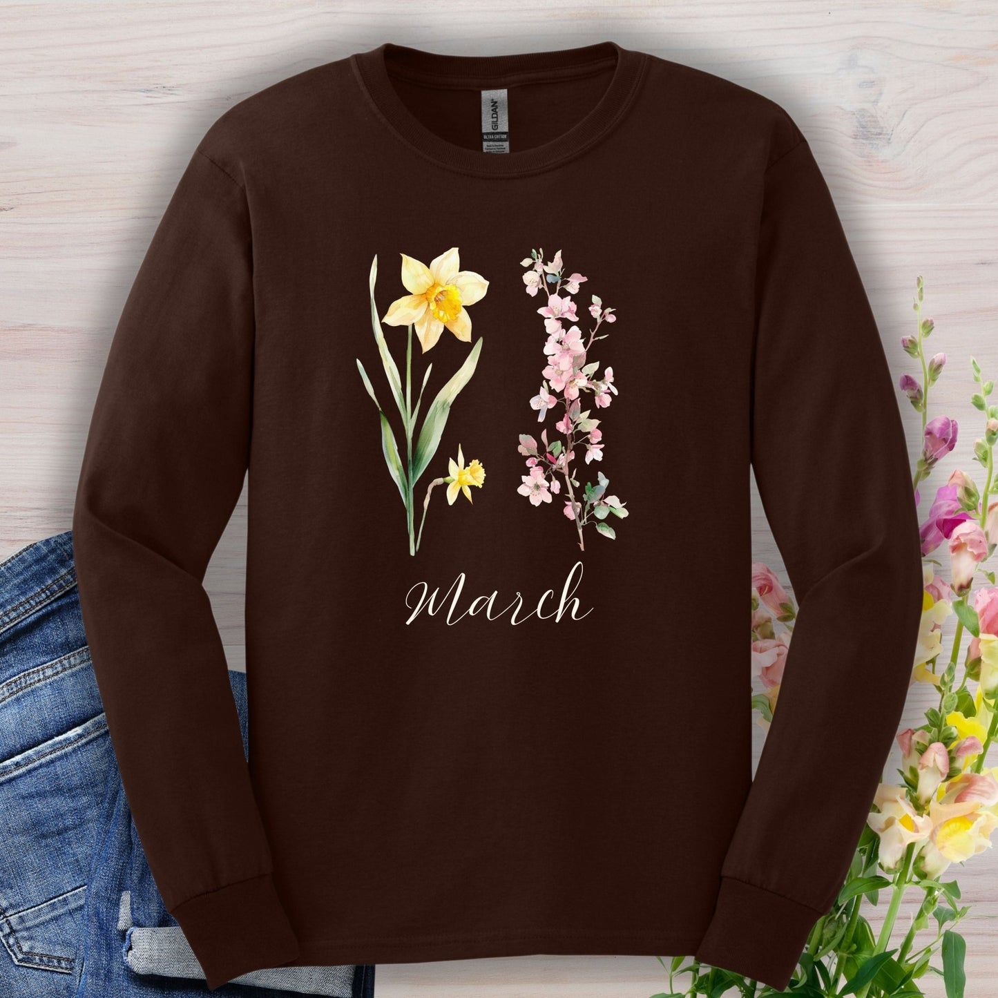 Dark chocolate long-sleeve tee with hand-drawn daffodil, pink cherry blossoms, and "March" script.