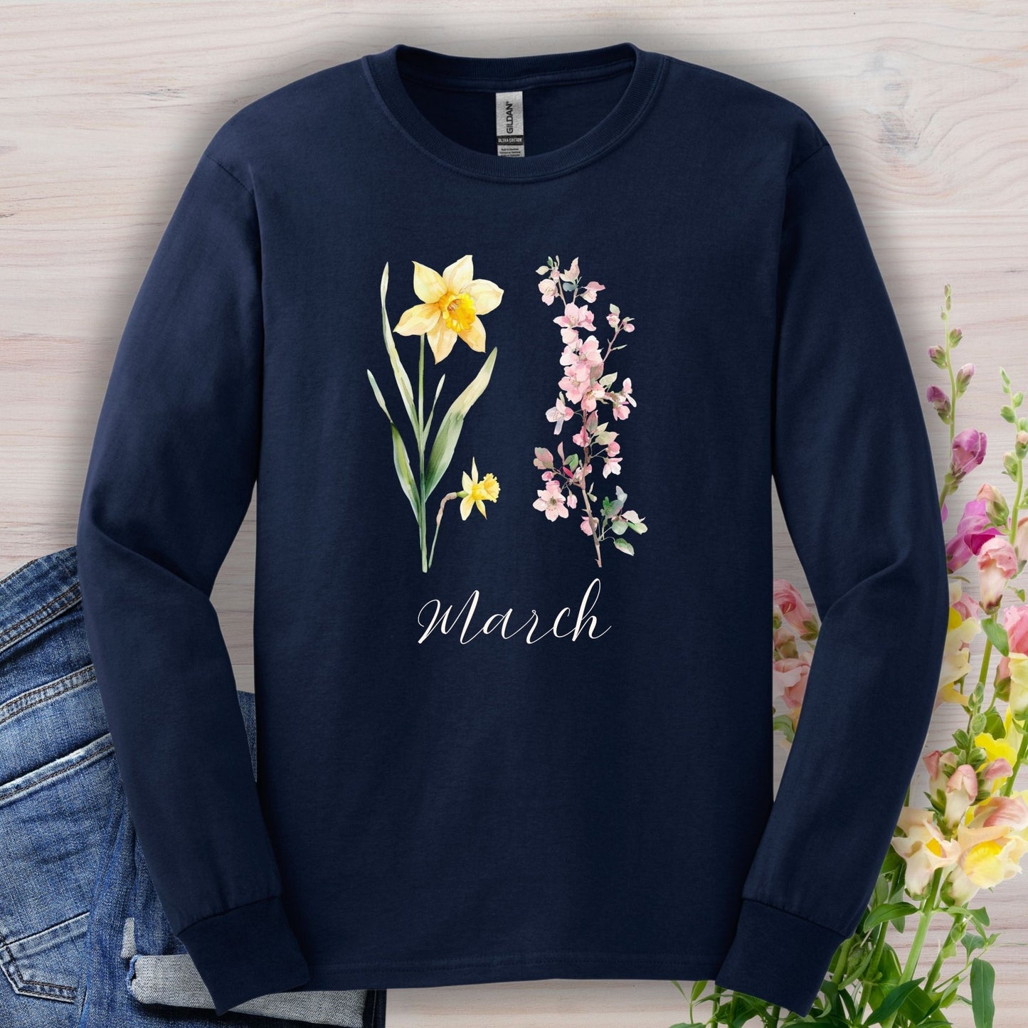 Navy long sleeve tee with hand-drawn yellow daffodils, pink cherry blossoms, and "March" script.