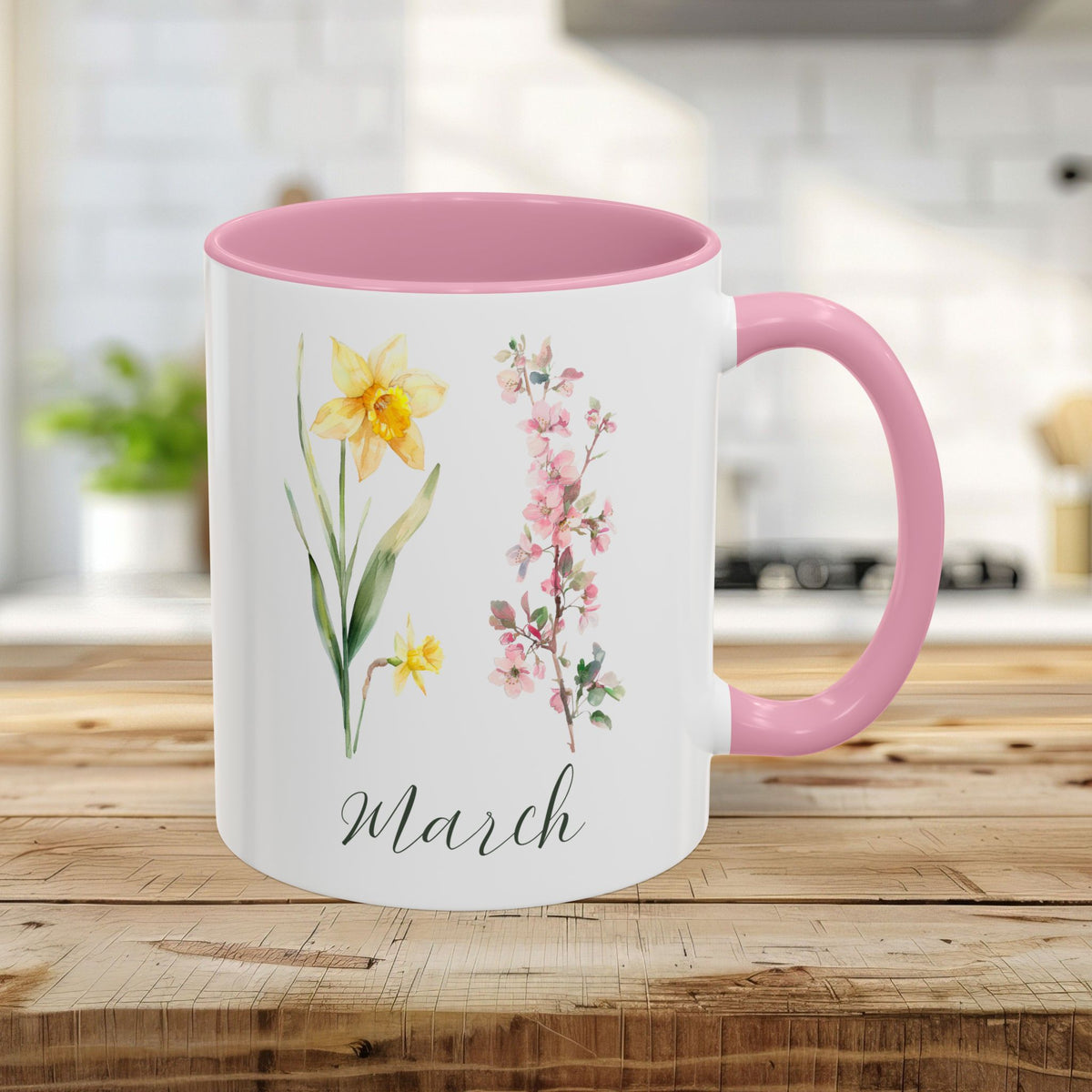 White ceramic 11oz mug with pink handle and interior, featuring watercolor daffodils and "March" script.