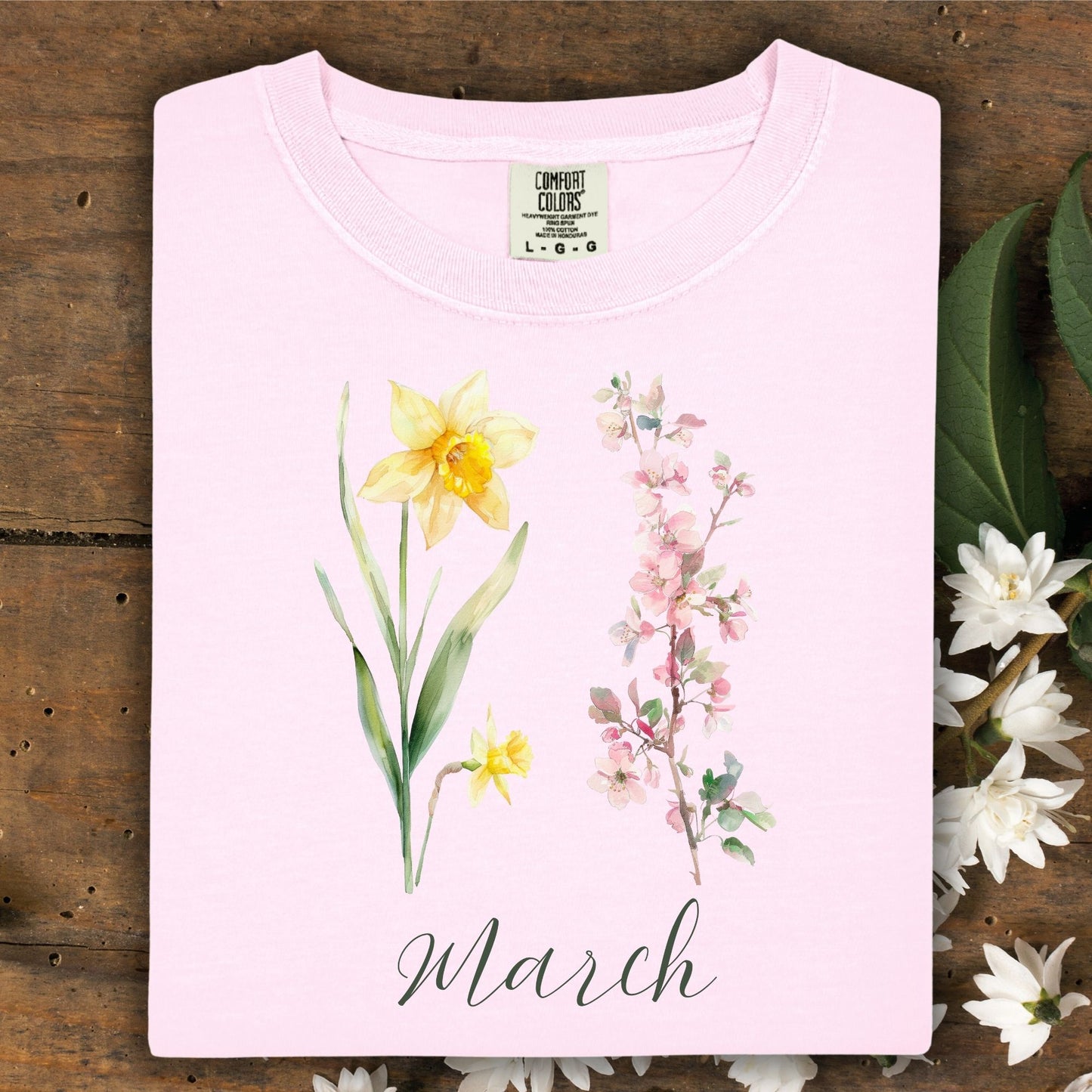 Blossom pink garment-dyed t-shirt with watercolor daffodil, cherry blossoms, and "March" script.
