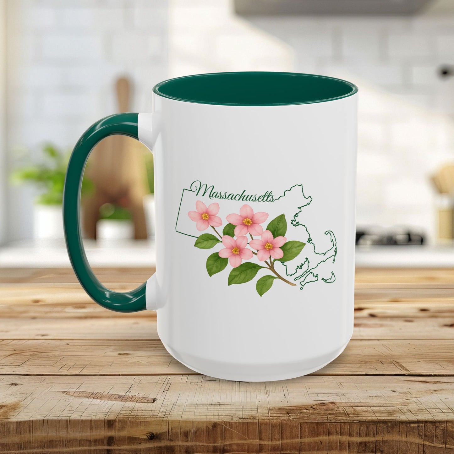 White ceramic mug with a green handle and interior, featuring a pink Mayflower design and Massachusetts state outline.