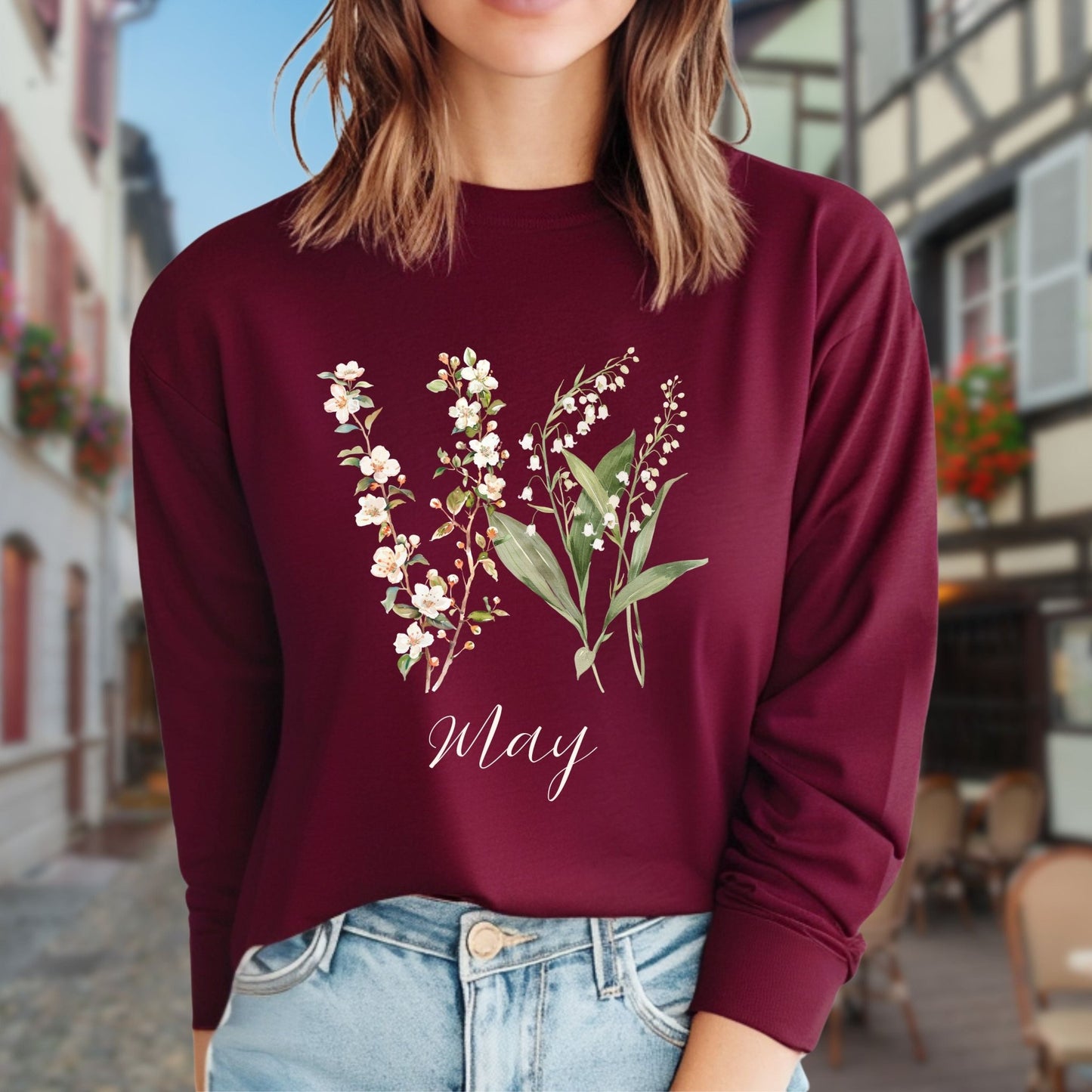 Maroon long-sleeve tee with watercolor lily of the valley and hawthorn blossoms, and "May" script.