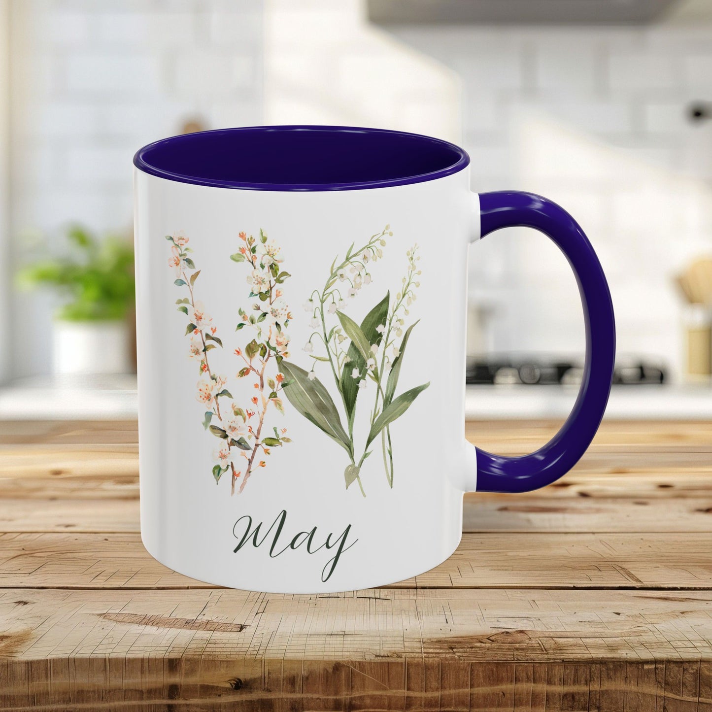 White ceramic 11oz May birth month flower mug with navy blue handle and interior, featuring lily of the valley and hawthorn.