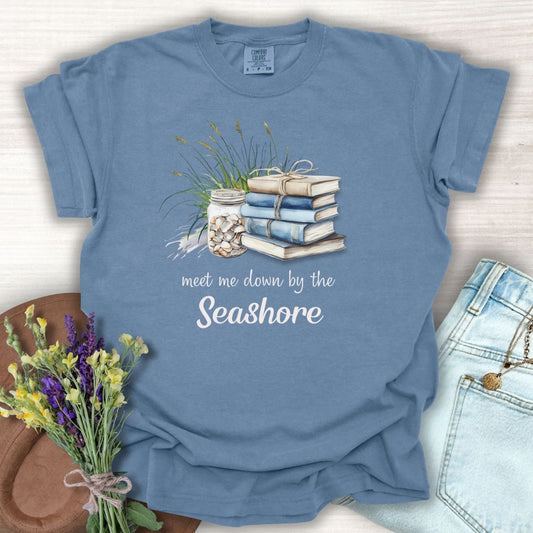 Blue Jean S t-shirt with "Meet Me Down By the Seashore" text, books, shells, and dune grass graphic.