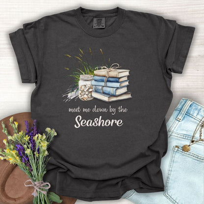Pepper S t-shirt with "meet me down by the Seashore" text, stacked books, shells, and dune grass design.