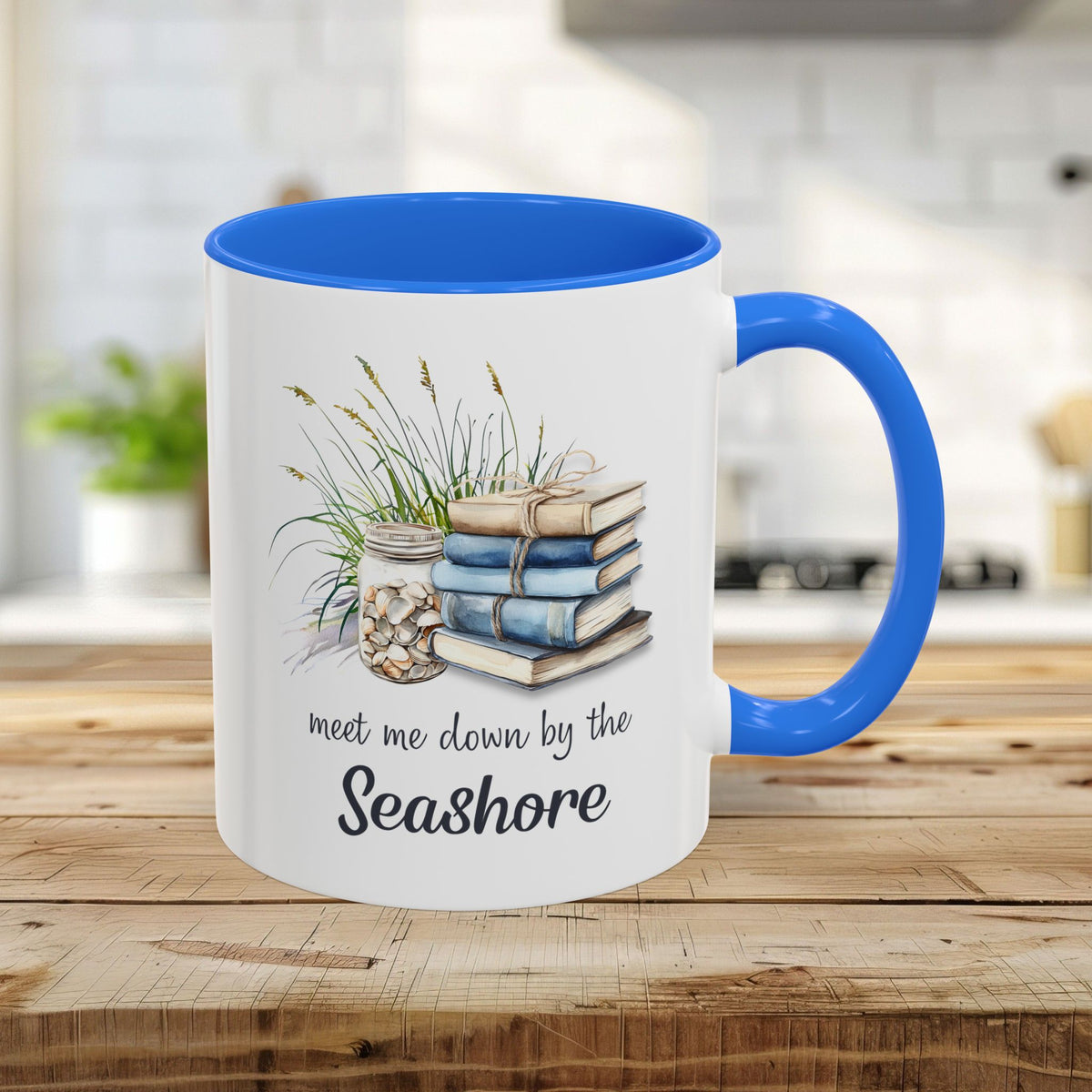 White ceramic 11oz mug with Cambridge Blue interior and handle, featuring watercolor stacked books, shells, and "meet me down by the Seashore.