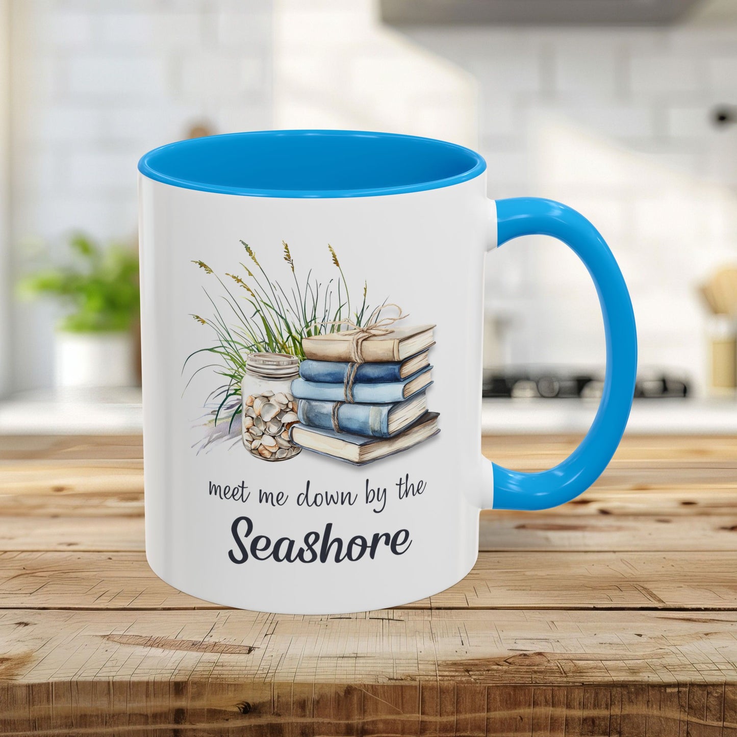 White 11oz ceramic mug with light blue interior and handle, featuring watercolor art of stacked books, beach grasses, and shells.