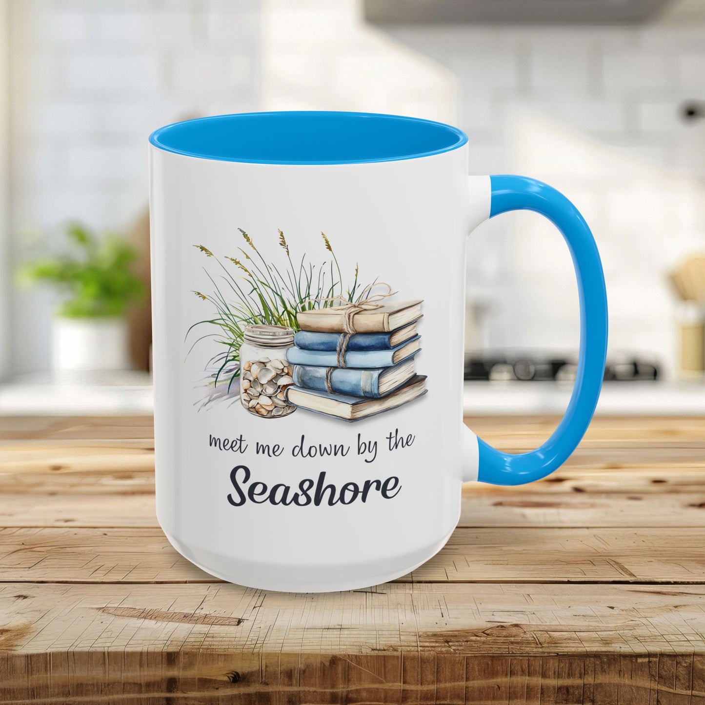 15oz ceramic mug with light blue interior/handle, watercolor art of stacked books, beach grasses, shells, and "meet me down by the Seashore.