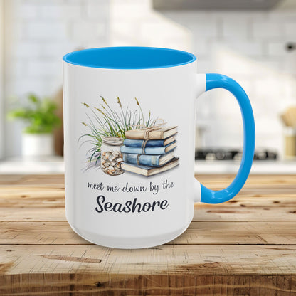 15oz ceramic mug with light blue interior/handle, watercolor art of stacked books, beach grasses, shells, and "meet me down by the Seashore.