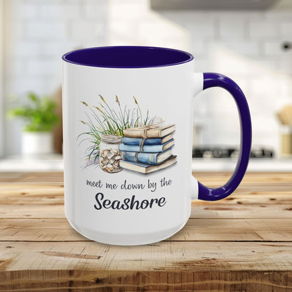 15oz white ceramic mug with blue interior and handle, featuring watercolor stacked books, beach grasses, shells, and "meet me down by the Seashore" text.