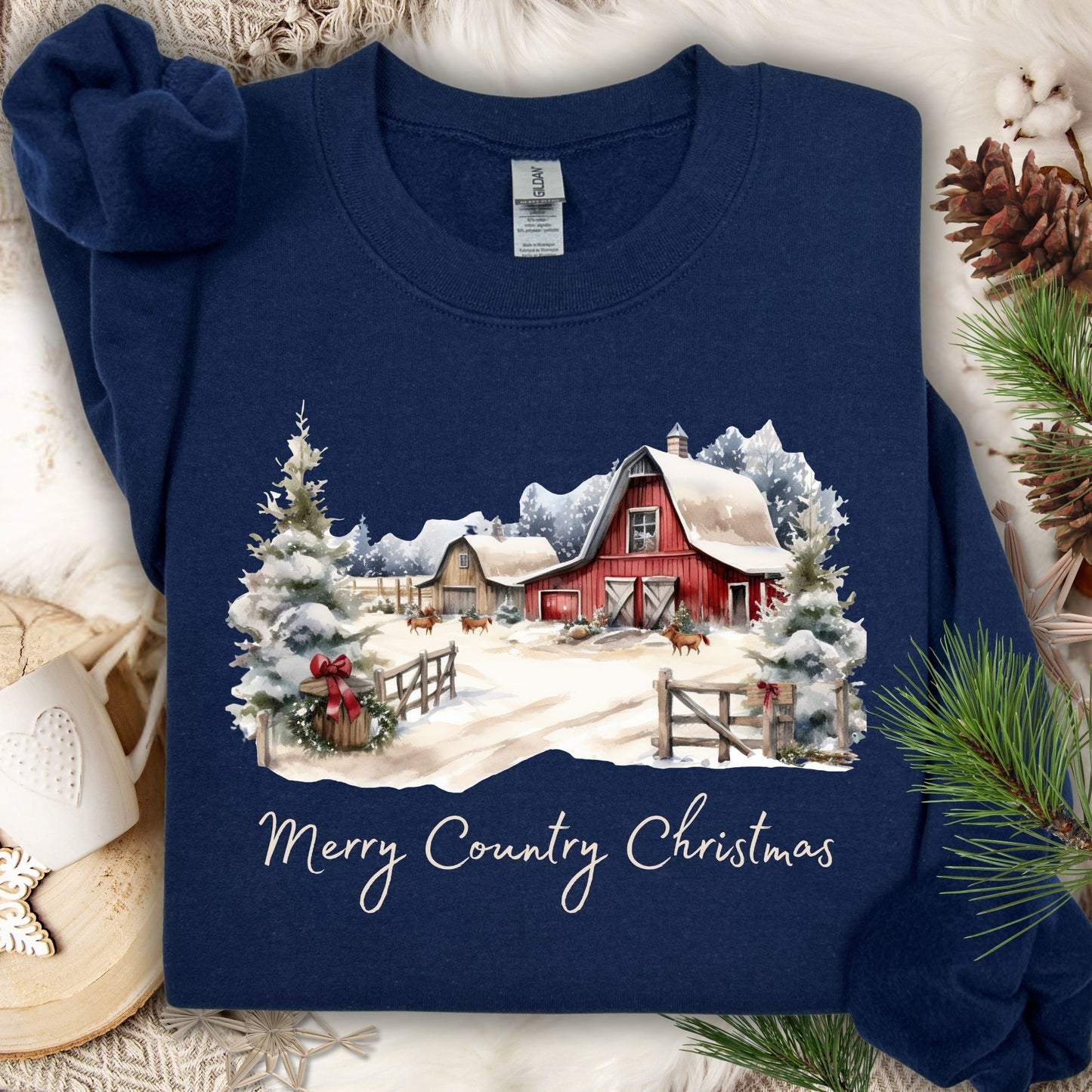 Navy Gildan sweatshirt with a watercolor snow-covered red barn, wreaths, evergreens, and "Merry Country Christmas" text.