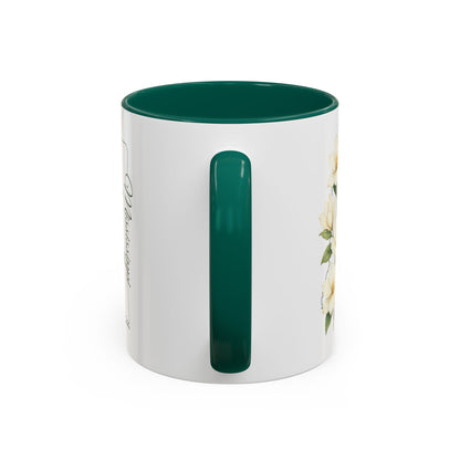 White ceramic mug with green handle and interior, featuring delicate magnolia blooms and "Mississippi" script.
