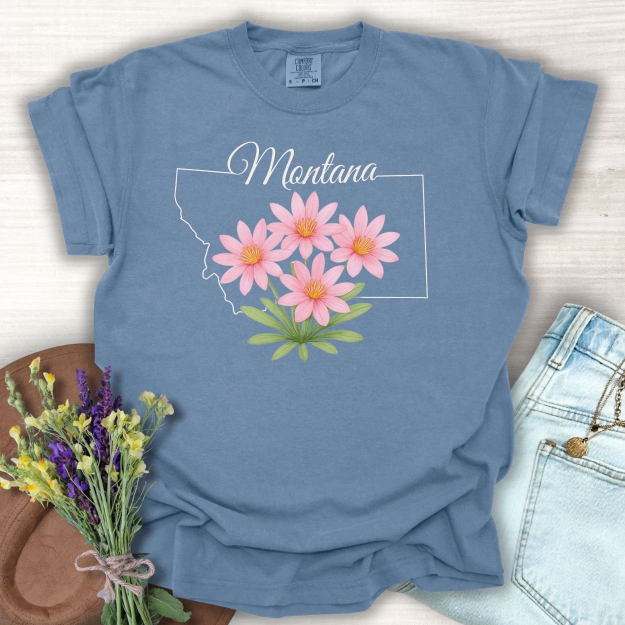 Blue Jean S Montana State Flower T-Shirt with pink Bitterroot wildflowers and a white outline of Montana.