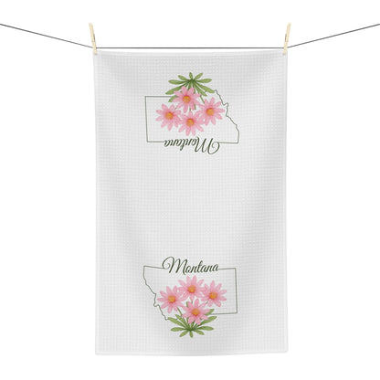 White microfiber tea towel with Montana outline and pink bitterroot flowers, hanging on a clothesline.