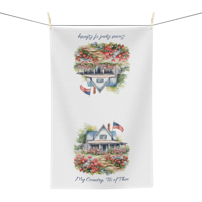 White microfiber tea towel with watercolor farmhouse, blooming garden, US flag, and patriotic text.