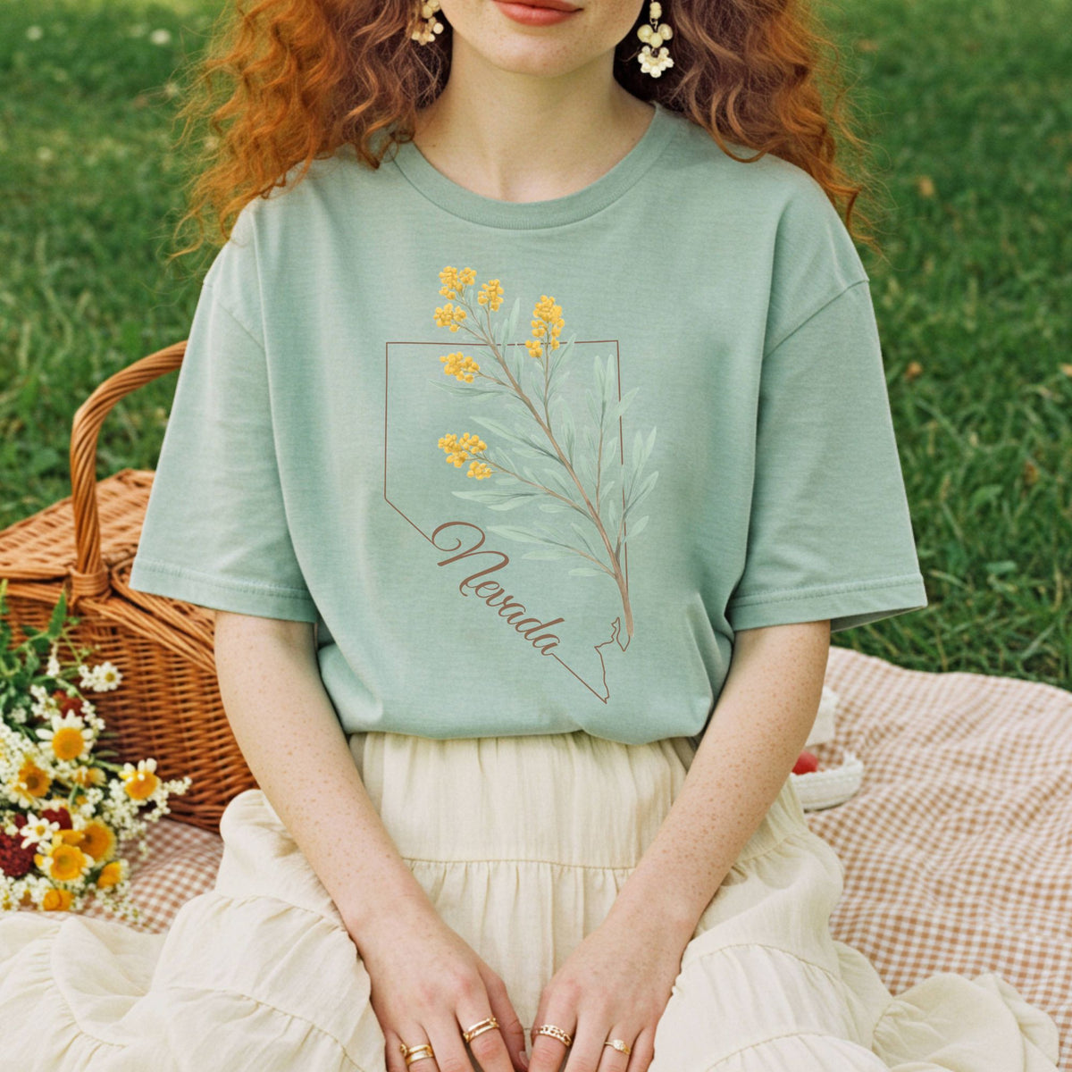 Sagebrush green relaxed-fit cotton t-shirt with Nevada state outline and yellow floral design.