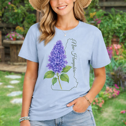 Woman in a light blue t-shirt with a watercolor lilac and New Hampshire outline.