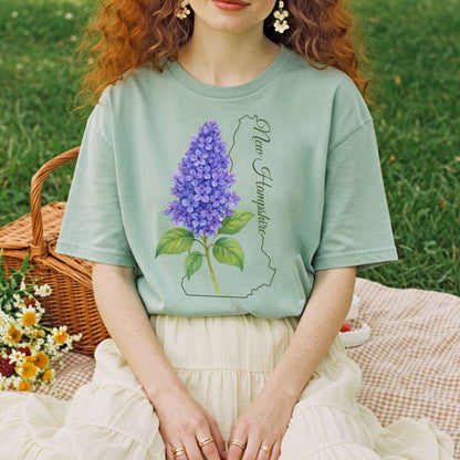 Garment-dyed sage green t-shirt with a watercolor blue lilac and New Hampshire outline.