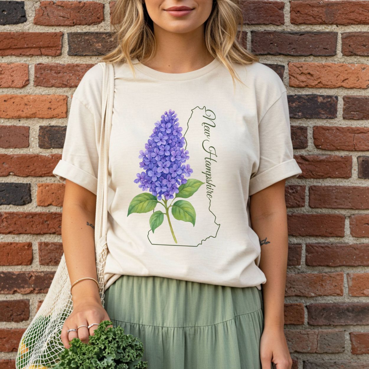 Woman in a relaxed-fit, garment-dyed t-shirt with a watercolor lilac and New Hampshire outline.