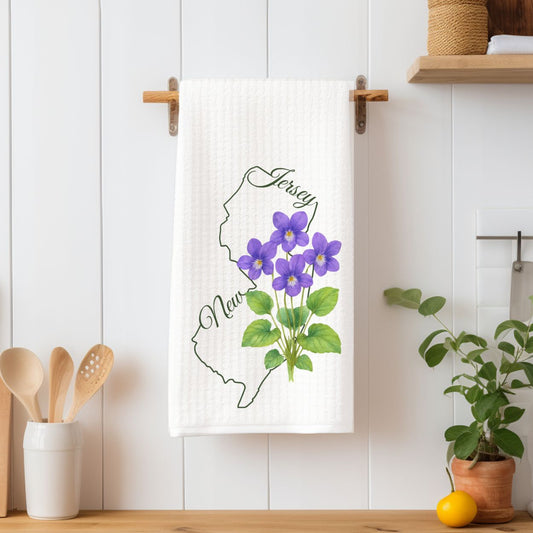 White microfiber tea towel with a green New Jersey outline and purple violet flowers.