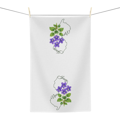 White microfiber tea towel with purple violet blooms and New Jersey outline, hanging on a clothesline.