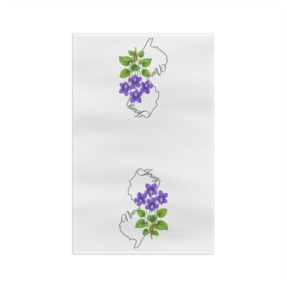 White microfiber tea towel with two outlines of New Jersey, each adorned with purple meadow violet blooms.