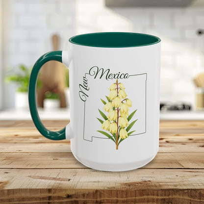 White ceramic mug with green handle and interior, featuring a New Mexico outline and Yucca flower illustration.