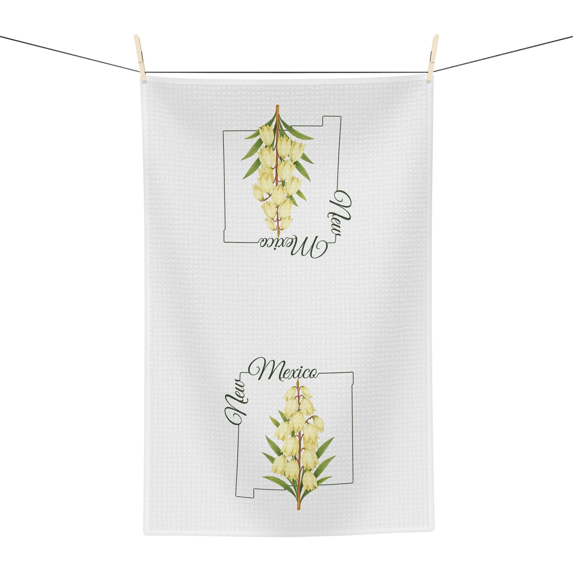 White microfiber tea towel with a watercolor yucca bloom and "New Mexico" text, hanging on a clothesline.