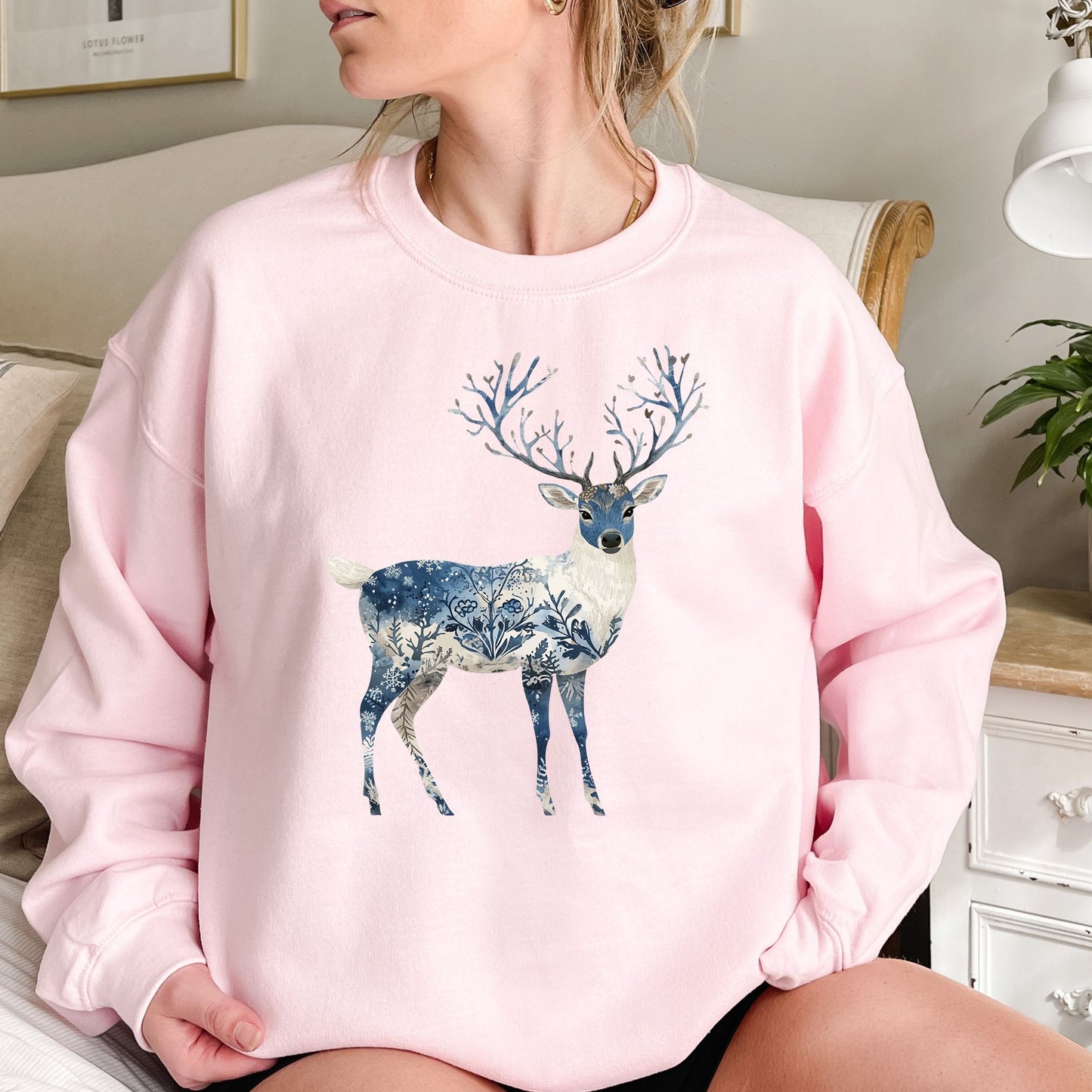 Pink cotton-poly sweatshirt with a stylized deer featuring blue botanical and frost patterns, and tree-like antlers.