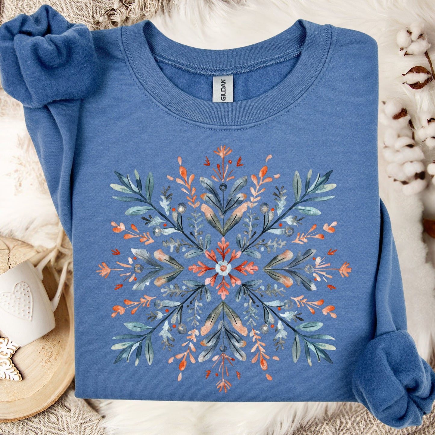 Indigo blue Gildan fleece sweatshirt with a watercolor Nordic snowflake design in red, blue, and green.