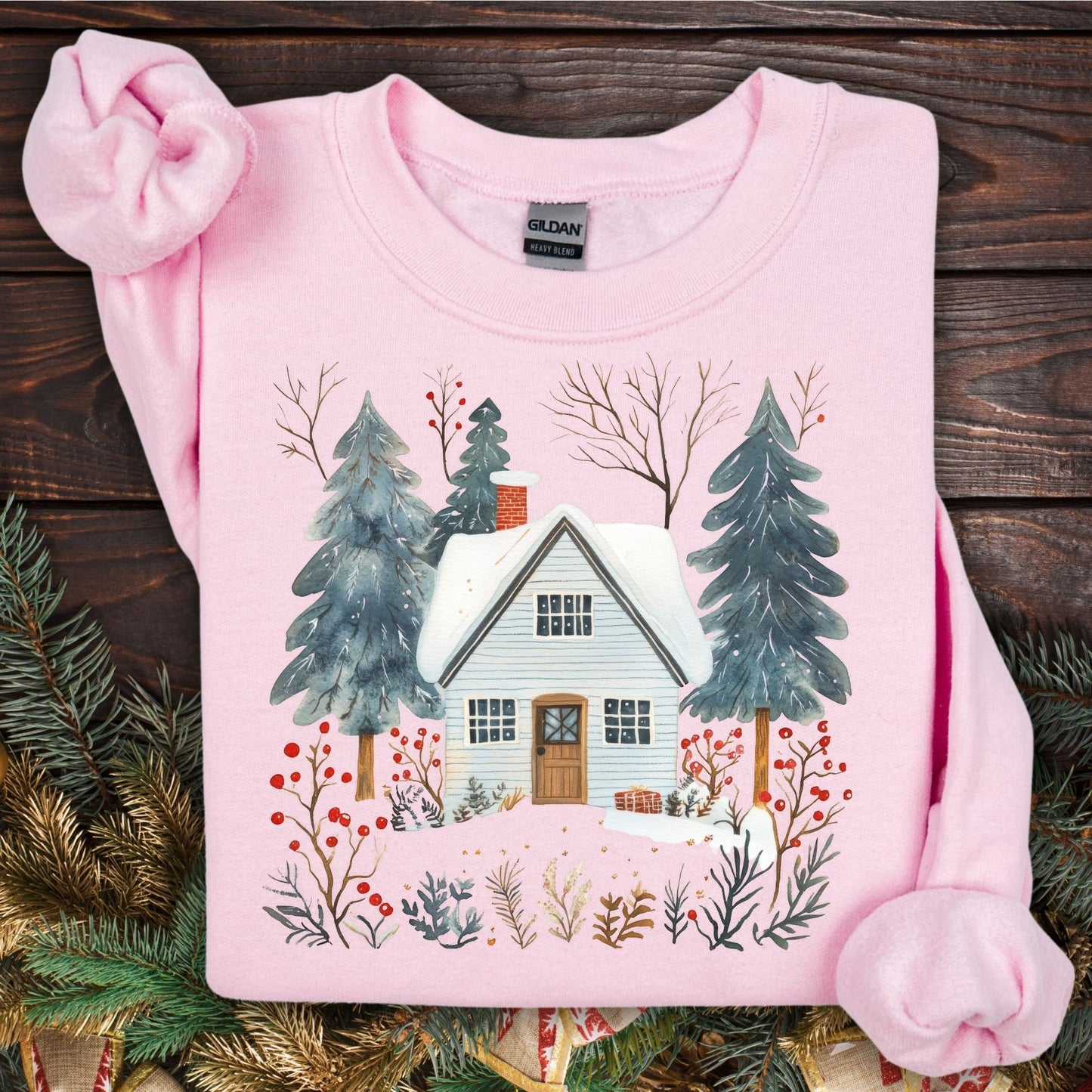 Light pink Nordic Winter Cabin Sweatshirt with a snowy cabin and pine trees design.