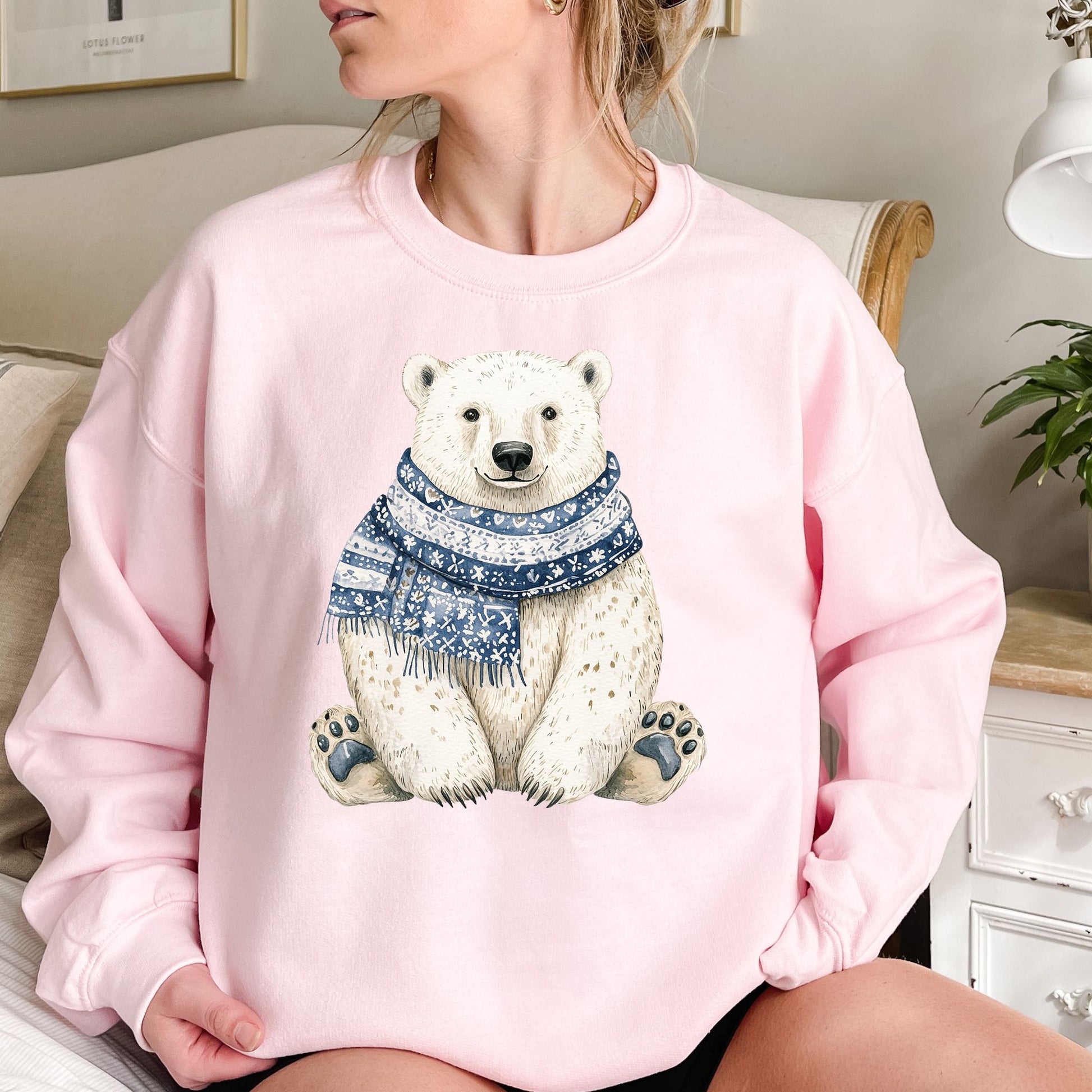 Pink sweatshirt with a detailed illustration of a sitting polar bear wearing a blue and white snowflake scarf.
