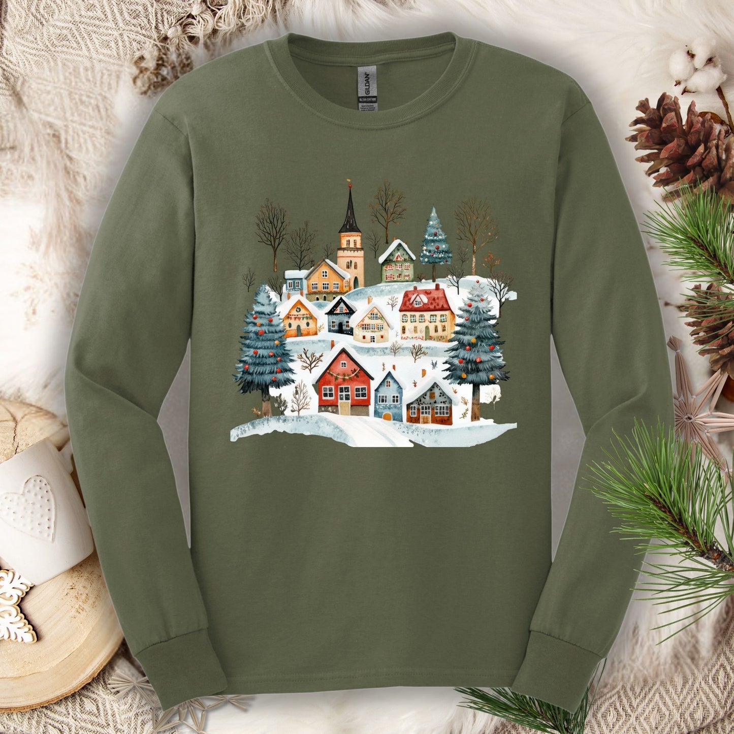 Military Green Gildan Softstyle long sleeve tee with a watercolor Nordic winter village design.