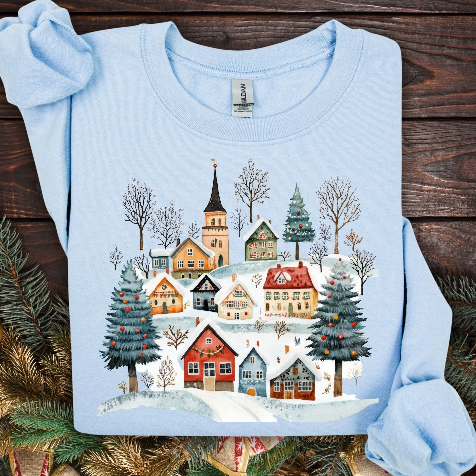 Light blue Nordic Winter Village sweatshirt with folk-art design of snow-covered cottages and trees.
