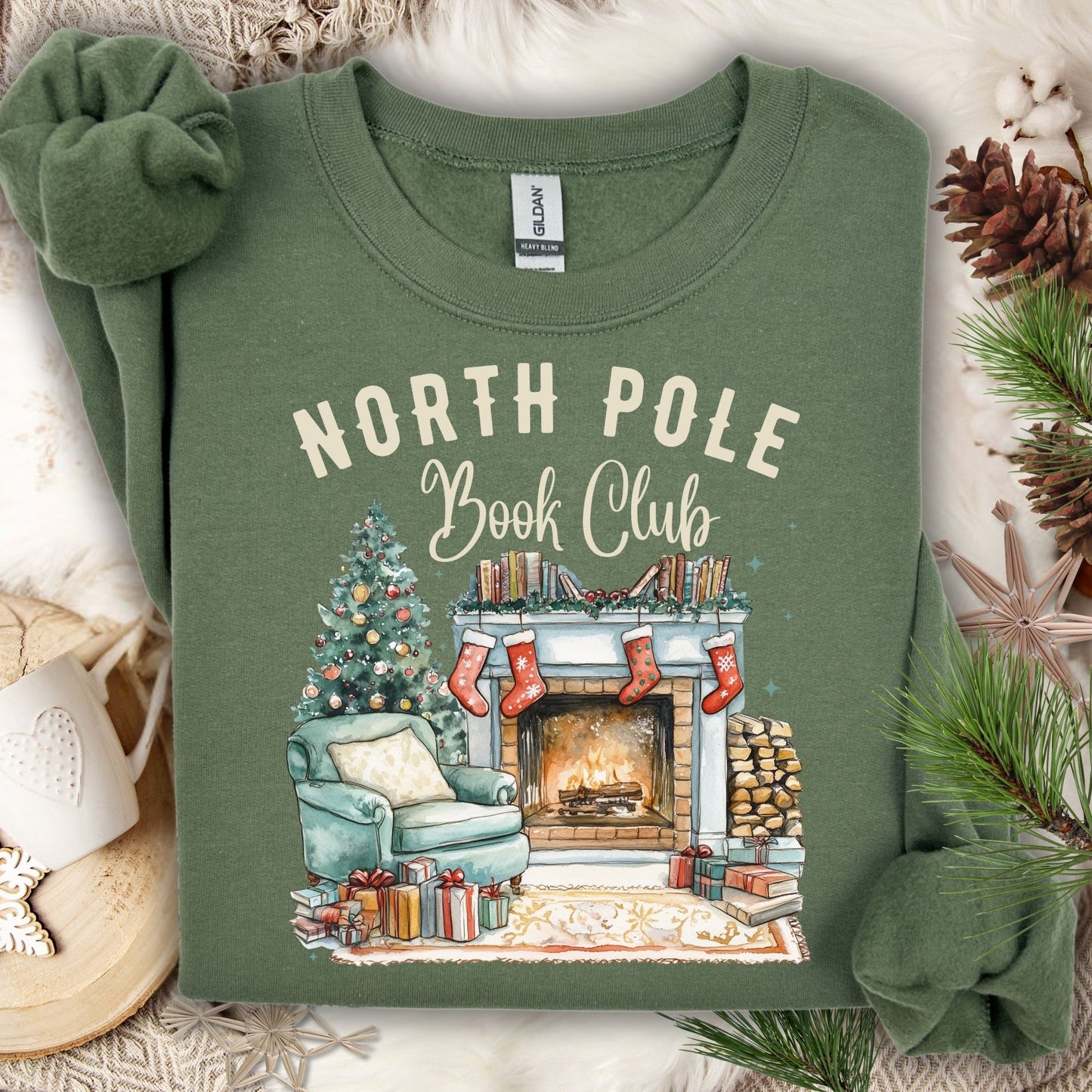 Military Green Gildan sweatshirt with "North Pole Book Club" text and a cozy Christmas fireplace scene.