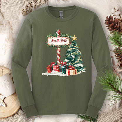 Military Green Gildan long sleeve tee with a watercolor North Pole sign, snowy tree, and gifts.