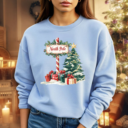 Light blue Gildan 18000 sweatshirt with a watercolor North Pole sign, Christmas tree, and gifts.