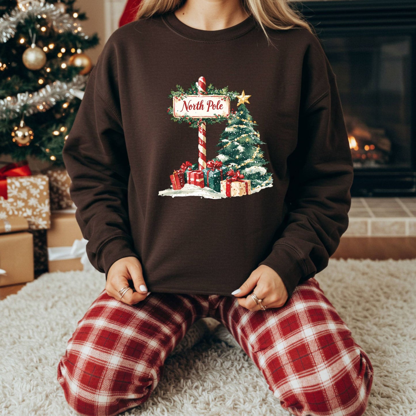 Brown North Pole Christmas sweatshirt with watercolor tree, gifts, and snowy details.