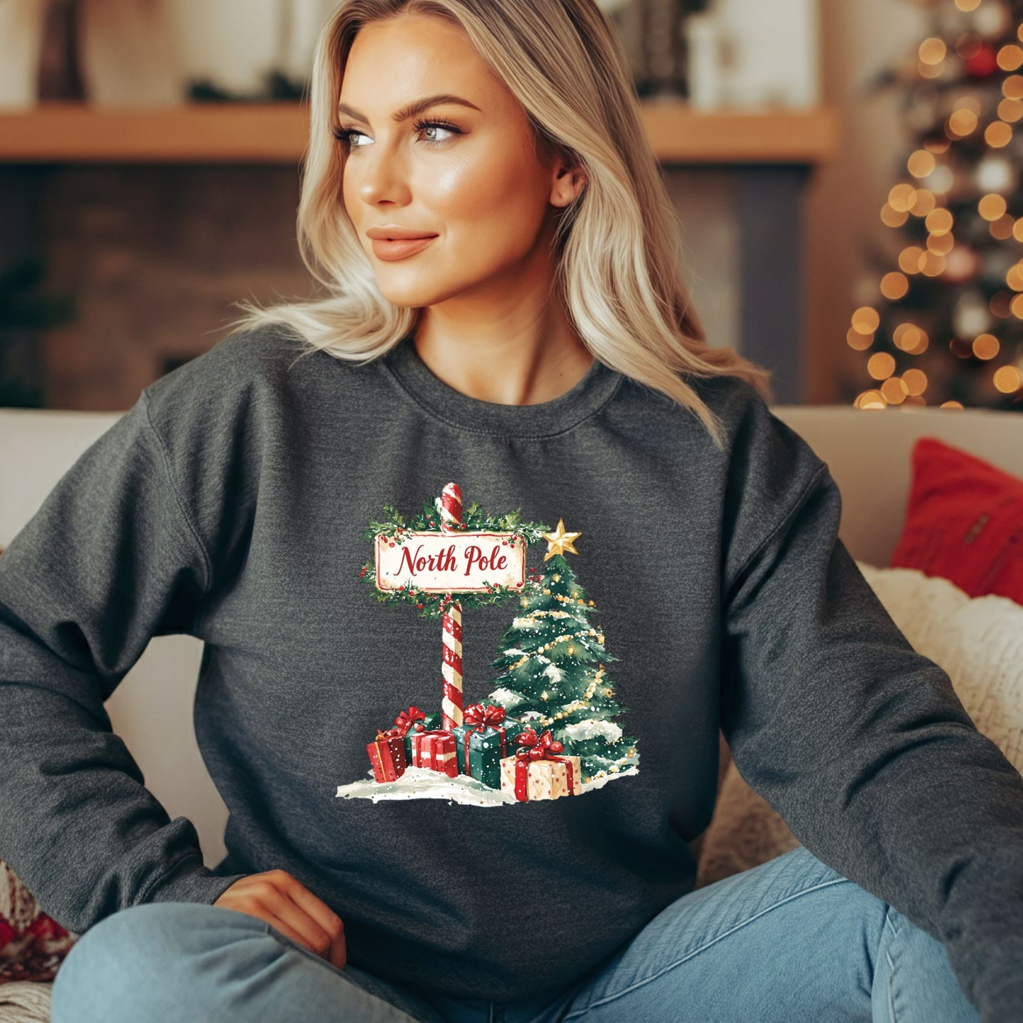 Woman wearing a dark gray North Pole watercolor Christmas sweatshirt with a festive tree and gifts.